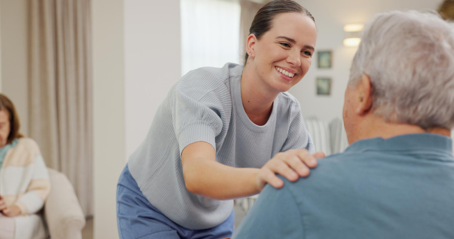 Lächelnde Betreuerin im Gespräch mit einem Senior